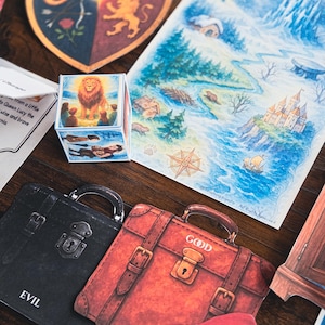 May include: A collection of illustrated cards and a cube featuring imagery of a lion, maps, and suitcases labeled "EVIL" and "GOOD." The artwork includes a shield with a lion and a map with a castle.