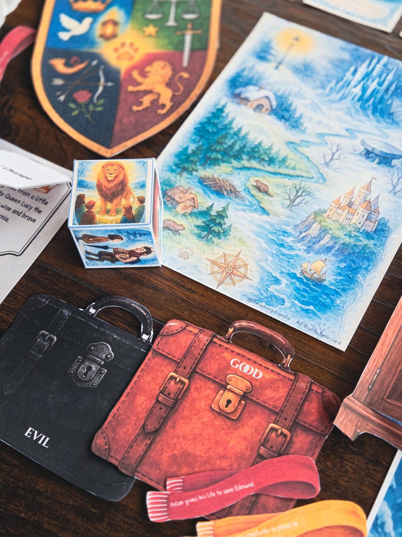 May include: A collection of illustrated cards and a cube featuring imagery of a lion, maps, and suitcases labeled "EVIL" and "GOOD." The artwork includes a shield with a lion and a map with a castle.