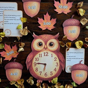 Op de afbeelding: Educatief materiaal voor het leren klokkijken. De afbeelding toont een klok in de vorm van een uil, eikel- en esdoornblad-uitsparingen met weergegeven tijden en kaarten met tijdgerelateerde vragen. Het kleurenpalet omvat bruin, oranje en geel.