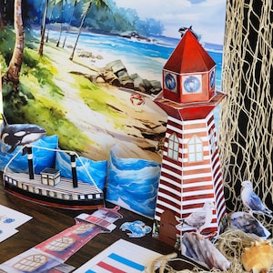 May include: A red and white striped lighthouse with a black roof and a white window. The lighthouse is decorated with a blue and white nautical design. The lighthouse is sitting on a table with a blue and white striped tablecloth. There is a blue and white striped beach towel behind the lighthouse.