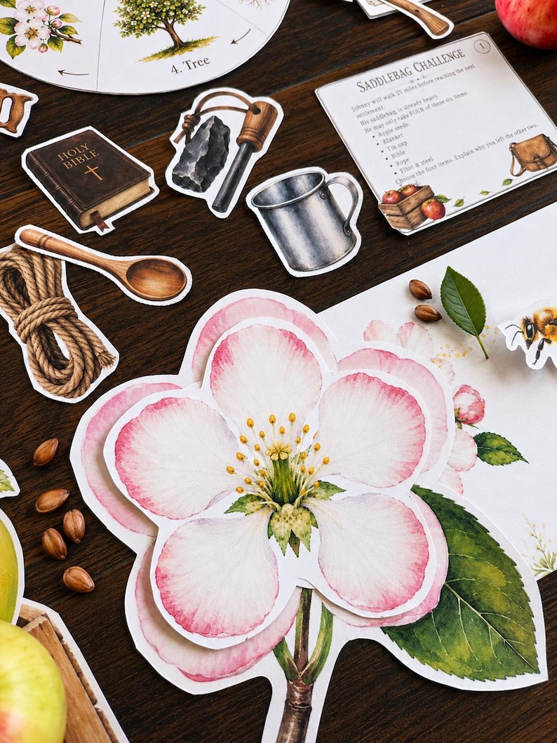 May include: A collection of educational paper cutouts featuring a large pink and white apple blossom, a Holy Bible, a flint and steel, a metal cup, a wooden spoon, a coil of rope, and a Saddlebag Challenge card with text and illustrations.