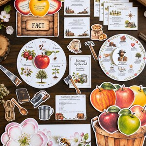 May include: A Johnny Appleseed educational activity set featuring a life cycle wheel, vocabulary guide, challenge cards, and various die-cut illustrations including apples, a wooden crate, a hammer, an axe, a bee, and a wooden basket.