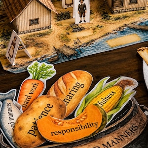 May include: A paper craft set featuring a printed village scene with three standing figures and a metal bowl labeled STEW OF GOOD MANNERS. Inside the bowl are paper cutouts of a fish, carrot, potato, bread, corn, and pumpkin with text.