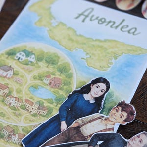 以下が含まれることがあります： 緑色の筆記体で「Avonlea」と書かれたカラフルなイラスト。青いドレスを着た女性、茶色のズボンをはいた男性、卵のバスケットを持った老婦人の切り抜きフィギュアが重ねられています。