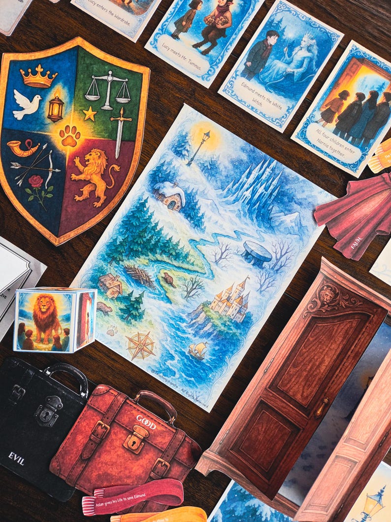 May include: A collection of illustrated cards, maps, and decorative items with a fantasy theme. Includes a shield with various symbols, a map of a snowy landscape, a red suitcase labeled "GOOD", and cards with text like "Lucy enters the wardrobe".