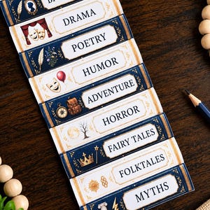 May include: A set of rectangular book genre labels featuring white backgrounds with navy blue and gold decorative borders. Each label displays a specific category name including Biography, Drama, Poetry, Humor, Adventure, Horror, Fairy Tales, Folktales, and Myths.
