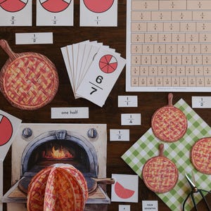 May include: Educational math set featuring fraction cards with red circle diagrams, a fraction wall chart, paper pie cutouts, and a printed oven scene. The set includes labels like one half and four sevenths, alongside a pair of black metal scissors.