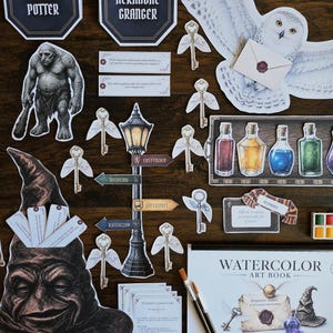 May include: A collection of Harry Potter themed paper cutouts including a Sorting Hat, a snowy owl with a letter, a troll, winged keys, potion bottles, a street sign, and a watercolour art book with two paintbrushes and a small paint palette.