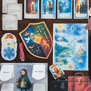 May include: A collection of illustrated cards and decorative items, including a shield, suitcases labeled "EVIL" and "GOOD", and a map. The cards feature text and images of a young girl, a lion, and scenes from a story. The items are arranged on a wooden surface.