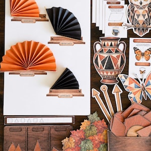 May include: An educational geometry set featuring paper fans demonstrating angles, geometric shape cards, an owl illustration, a Greek-style vase, a butterfly, wooden triangle sorting boards, and a collection of paper autumn leaves on a dark surface.
