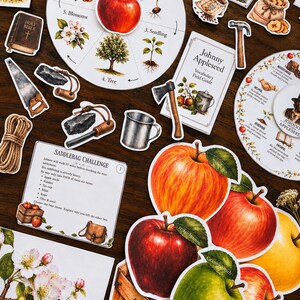 May include: A collection of educational paper cutouts featuring a life cycle wheel of an apple, Johnny Appleseed vocabulary cards, a saddlebag challenge card, and various illustrations of apples, tools, a rope, a bible, and a bee on a branch.
