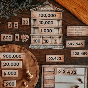 May include: An educational math set featuring wooden-style number tiles and boards. Includes a house-shaped place value chart, a rectangular form board with 'Standard Form', 'Expanded Form', and 'Word Form' labels, and various number tiles.