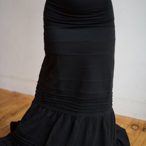 May include: A black skirt with a ruffled hem and multiple layers. The skirt is made of a soft, flowing fabric.