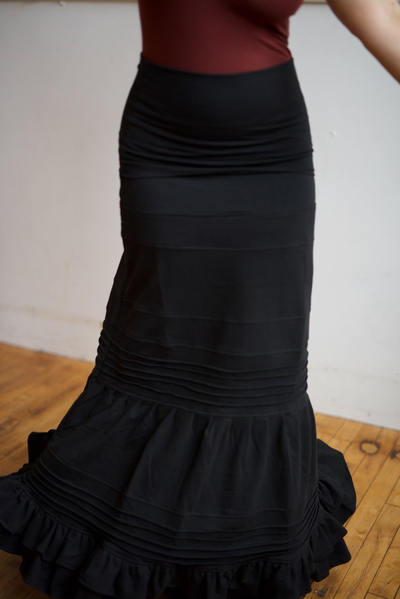 May include: A black skirt with a ruffled hem and multiple layers. The skirt is made of a soft, flowing fabric.