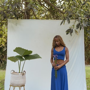 May include: A royal blue two-piece set consisting of a sleeveless cropped tank top and a matching high-waisted maxi skirt. The outfit is a solid, vibrant blue color with a simple, clean design, featuring a fitted top and a long, flowing skirt.