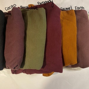 May include: A set of ten ribbed fabric swatches in various colors, including black, cacao, burnt olive, burgundy, caramel, earth, and cream.