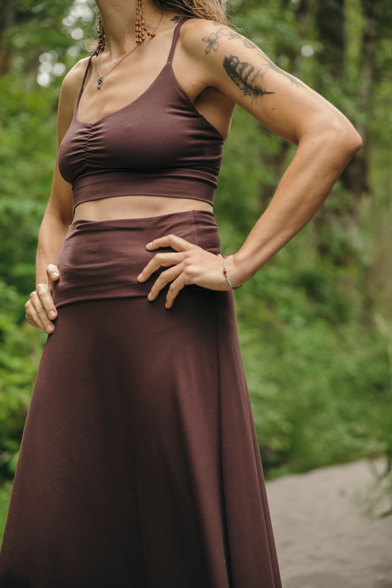May include: A dark brown two-piece set consisting of a cropped tank top with a ruched center detail and thin spaghetti straps, paired with a high-waisted, floor-length skirt featuring a wide, flat waistband that sits smoothly against the torso.