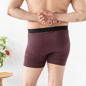 Puede incluir: Un par de b&oacute;xers color marr&oacute;n con una cintura negra. La persona lleva la ropa interior y tiene un tatuaje en la espalda.
