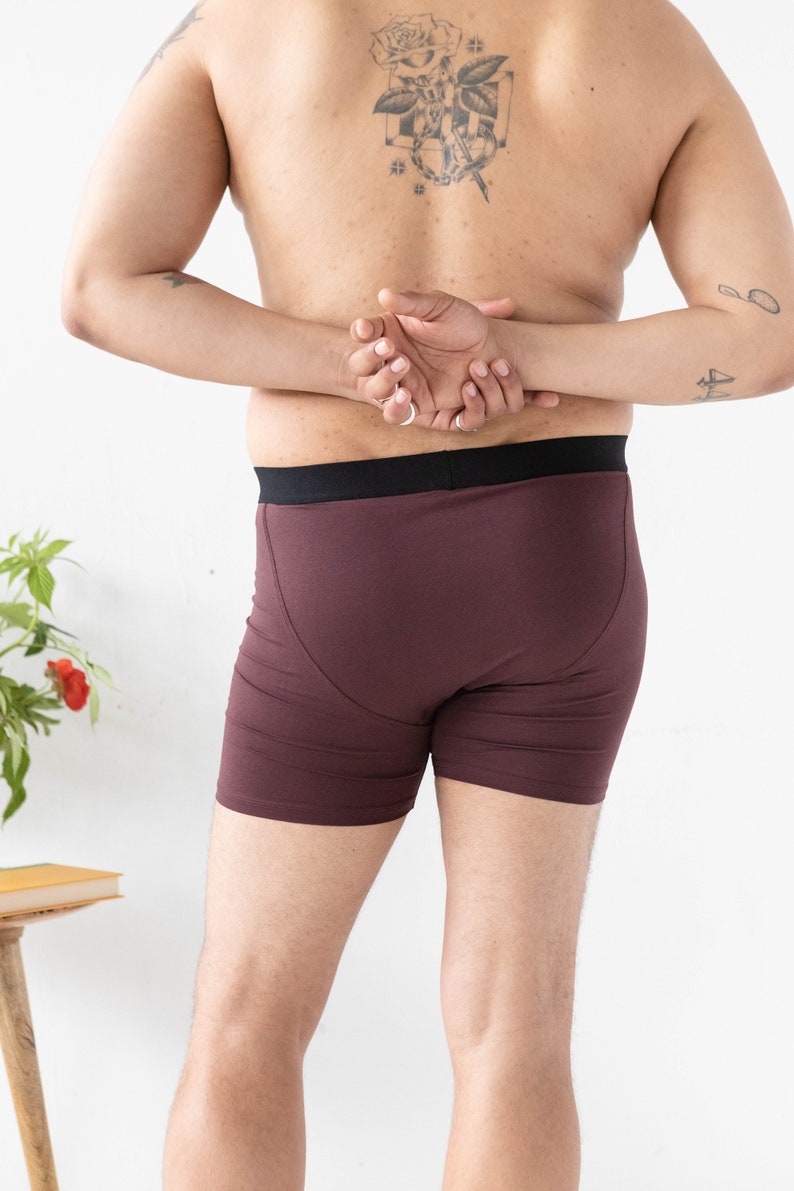 Puede incluir: Un par de b&oacute;xers color marr&oacute;n con una cintura negra. La persona lleva la ropa interior y tiene un tatuaje en la espalda.