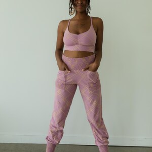 May include: A matching athletic set in a mauve color with a plaid pattern. The set includes a sports bra and high-waisted joggers. The joggers have pockets and elastic cuffs. The outfit is designed for comfort and style.