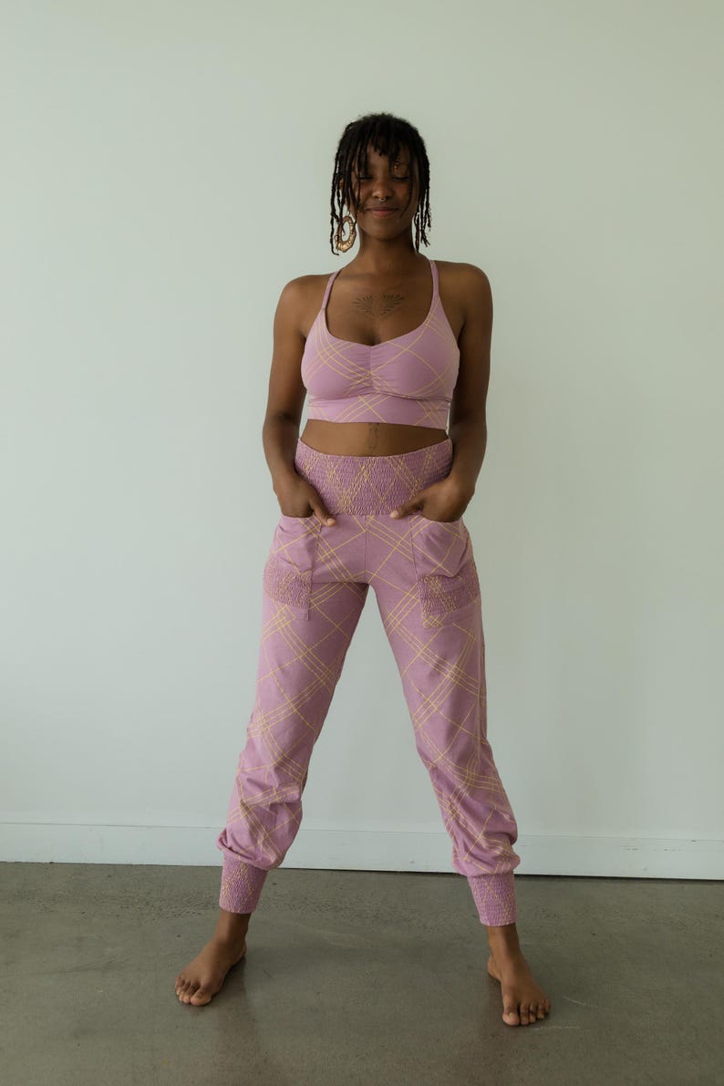 May include: A matching athletic set in a mauve color with a plaid pattern. The set includes a sports bra and high-waisted joggers. The joggers have pockets and elastic cuffs. The outfit is designed for comfort and style.