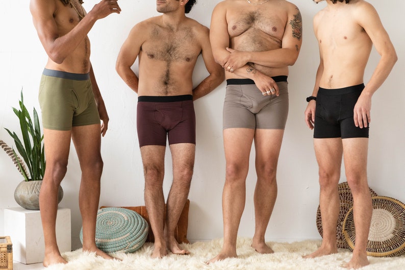 Puede incluir: Cuatro hombres con calzoncillos de diferentes colores. Los calzoncillos son todos de un estilo similar, con una cintura ancha y un ajuste holgado. Los hombres est&aacute;n de pie frente a una pared blanca.