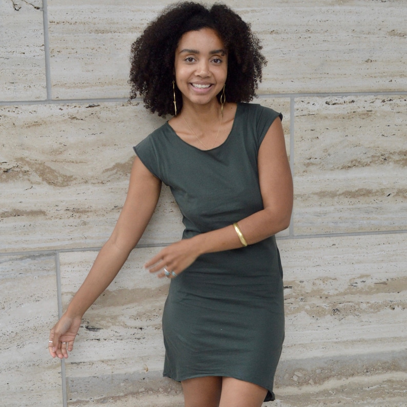 May include: A dark olive green short-sleeved dress with a round neckline and a raw-edge hem. The garment features a simple, fitted silhouette that reaches above the knee, crafted from a solid-colored fabric without any patterns or additional embellishments.