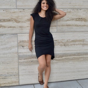 May include: A black knee-length dress with short sleeves, a round neckline, and a slightly asymmetrical hemline. The garment features a fitted bodice and a relaxed skirt section, providing a simple and clean silhouette for everyday wear.