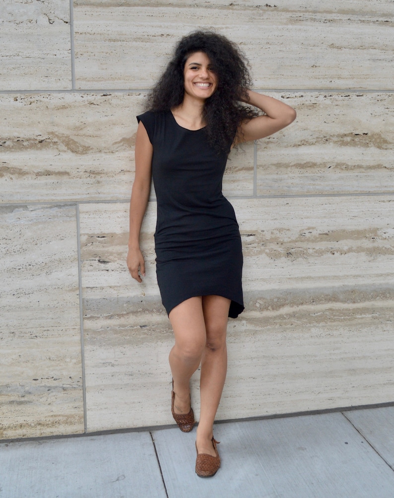 May include: A black knee-length dress with short sleeves, a round neckline, and a slightly asymmetrical hemline. The garment features a fitted bodice and a relaxed skirt section, providing a simple and clean silhouette for everyday wear.