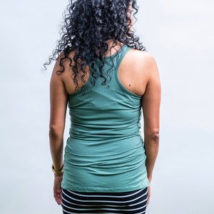 May include: A woman wearing a green tank top and a black and white striped skirt.