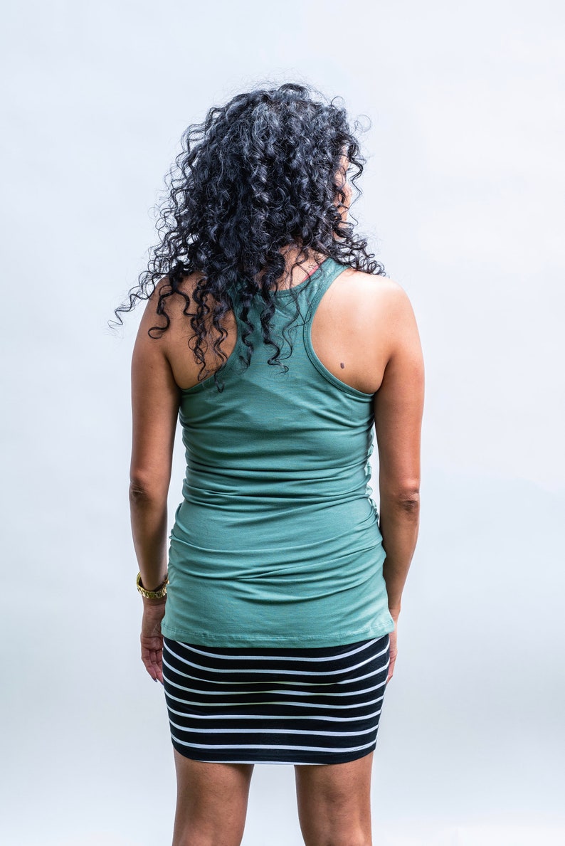 May include: A woman wearing a green tank top and a black and white striped skirt.