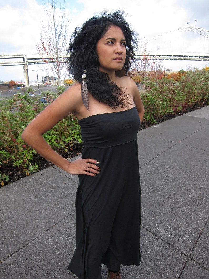 May include: A black strapless maxi dress with a fitted bodice and a flowing skirt. The garment features a simple, solid black design with a straight neckline and a long, loose-fitting silhouette that extends down to the lower legs.