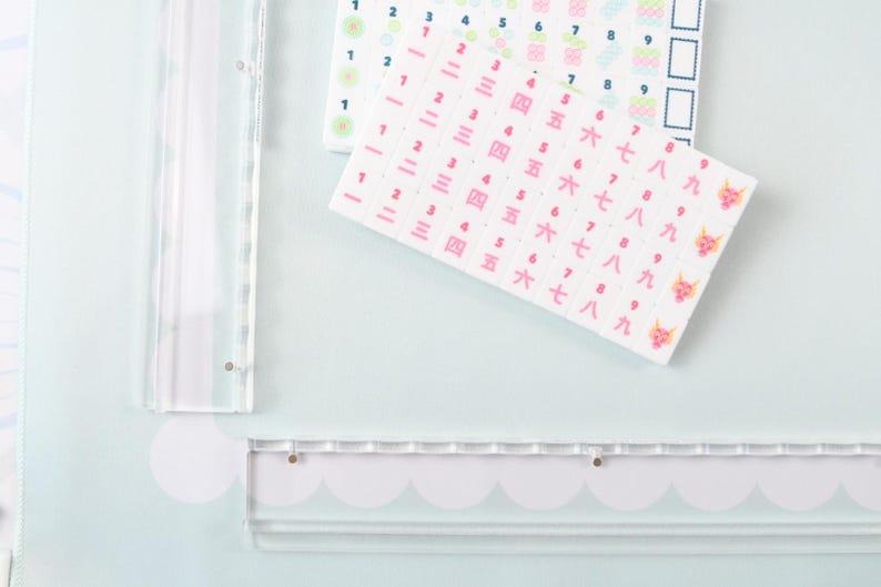 May include: Two sheets of rectangular stickers featuring rows of numbers. One sheet displays Arabic numerals in blue and green, while the other shows pink Chinese characters for numbers one through nine, ending with a small pink dragon icon.