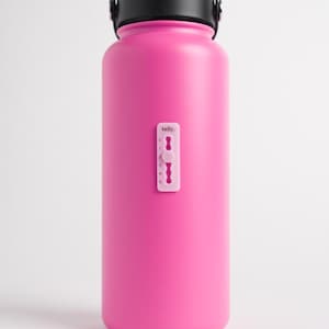 May include: A bright pink insulated water bottle with a black handle and lid. A small white tally marker is attached to the side. The word "tally" is printed on the marker.