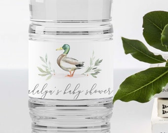 May include: A clear plastic water bottle with a white label featuring a watercolor illustration of a duck and the text "[Name]'s baby shower".