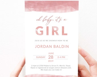 Puede incluir: Una invitación a un baby shower con un diseño de acuarela en tonos rosados. El texto dice "oh baby, it's a GIRL" e incluye los detalles del evento: fecha, hora y lugar. La invitación está sostenida por dos manos.