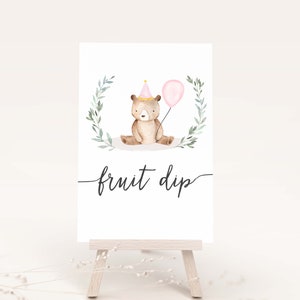 May include: A printable sign with a watercolor illustration of a brown bear wearing a pink party hat and holding a pink balloon. The sign says "fruit dip" in cursive.