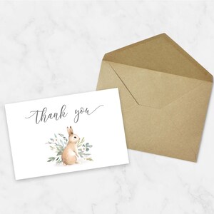 May include: A white thank you card with a watercolor illustration of a brown bunny rabbit surrounded by green leaves and white flowers. The text "Thank you" is written in cursive on the card.