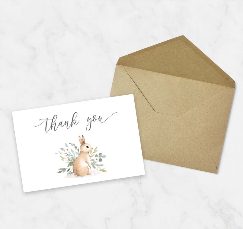 May include: A white thank you card with a watercolor illustration of a brown bunny rabbit surrounded by green leaves and white flowers. The text "Thank you" is written in cursive on the card.