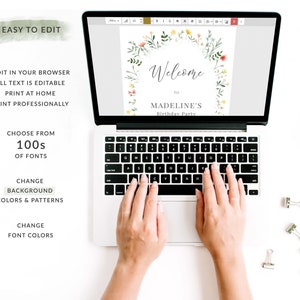 May include: A laptop computer displaying a welcome sign with a floral wreath design. The sign says "Welcome to Madeline's Birthday Party". The laptop is on a white surface with silver paper clips.