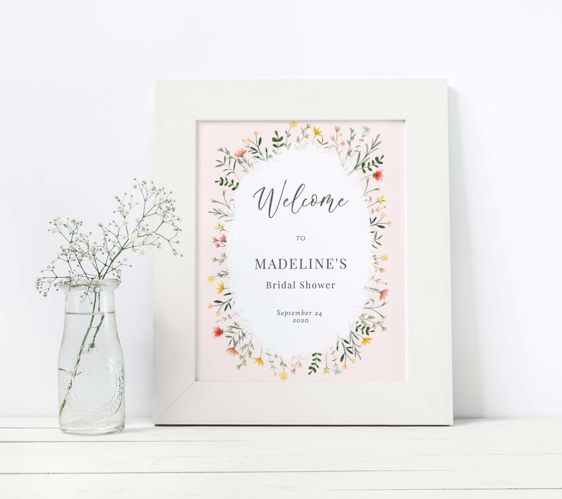 May include: A printable bridal shower welcome sign with a floral wreath design. The sign is on a pink background and says "Welcome to Madeline's Bridal Shower, September 24, 2020".
