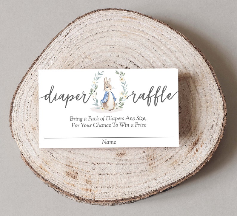 May include: A white card with a watercolor illustration of a rabbit wearing a blue jacket. The card says "diaper raffle" and "Bring a pack of diapers any size, for your chance to win a prize". There is a line for a name at the bottom.