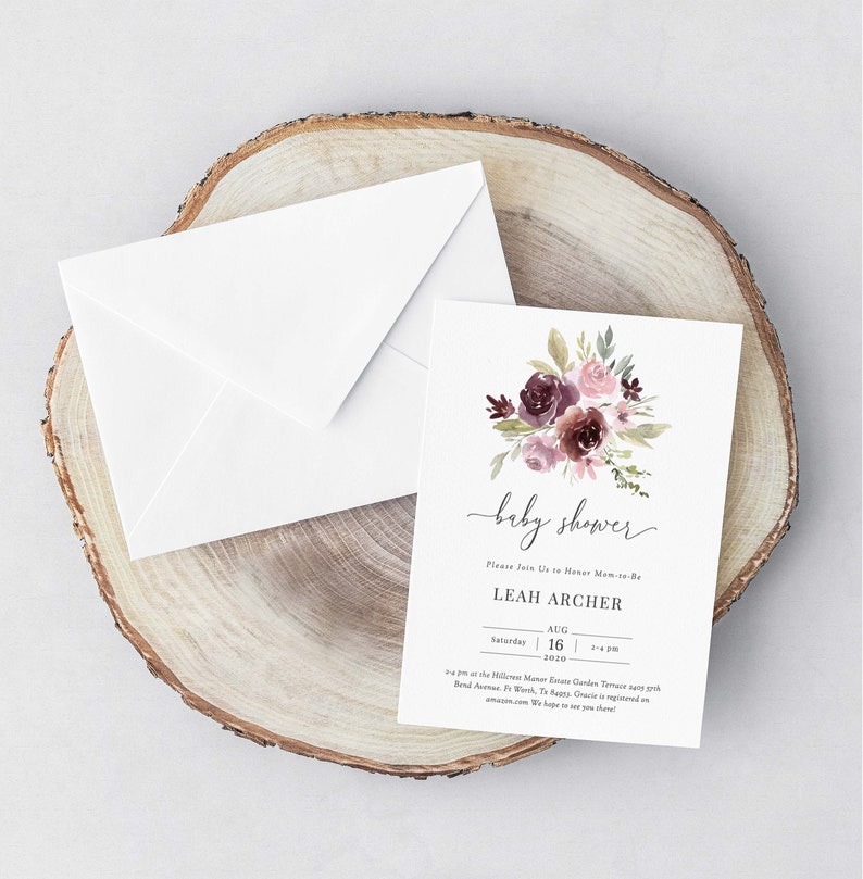 May include: A white card with a floral design in shades of pink and purple. The text on the card reads "baby shower" and "Please Join Us to Honor Mom-to-Be Leah Archer" with the date and time of the event.