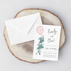 May include: A pink and green watercolor invitation for a first birthday party. The invitation features a pink balloon with green leaves and white flowers. The text on the invitation reads "Emily is One!" and includes the date and time of the party.