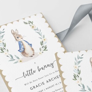 May include: A baby shower invitation with a watercolor illustration of a bunny rabbit wearing a blue jacket. The invitation reads "A little bunny Will Be Here Soon! Join Us to Honor Gracie Archer Saturday August 12 | 2-4 PM 1234 Garden Terrace"