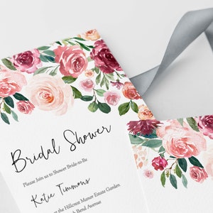 Op de afbeelding: Een bruidsdouche-uitnodiging met een aquarelbloemendesign in roze en bordeaux tinten. De tekst luidt "Bridal Shower" en "Please Join us to Shower Bride-to-Be Katie Timmons at the Hillcrest Manor Estate Garden Bend Avenue".