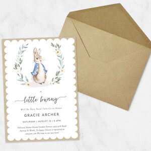 May include: A baby shower invitation with a watercolor illustration of Peter Rabbit in a blue jacket and a wreath of white flowers and green leaves. The text reads "A little bunny Will Be Here Soon! Join Us to Honor Gracie Archer Saturday August 12 | 2-4PM Hillcrest Manor Estate Garden Terrace 2405 37th Bend Avenue Ft Worth, Tx 84053. Gracie is registered on amazon.com We hope to see you there!"