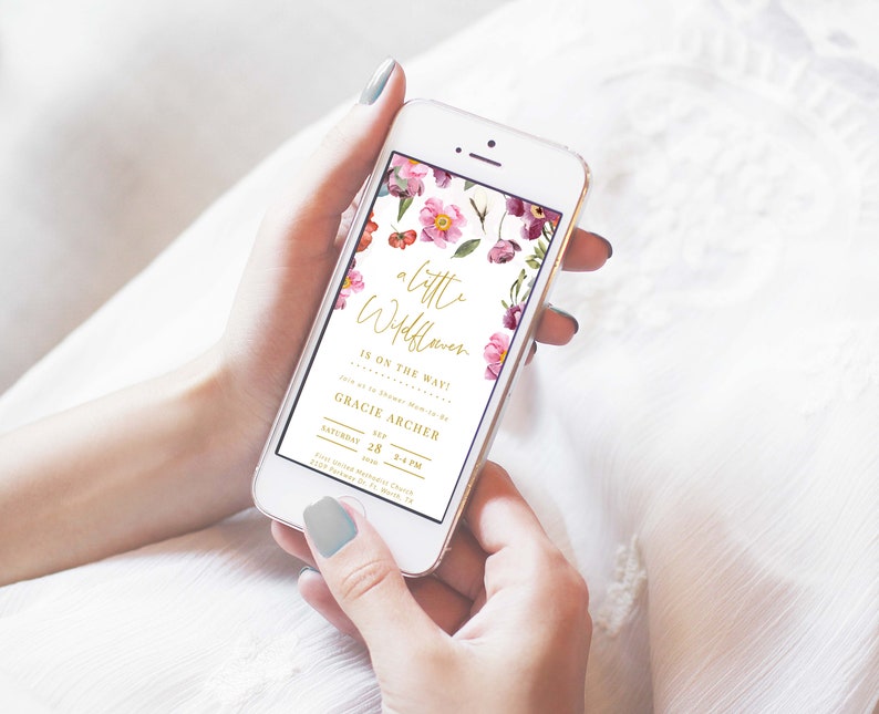May include: A floral baby shower invitation on a smartphone screen. The invitation features a watercolor floral design with pink and purple flowers. The text reads "a little wildflower is on the way!" and "Gracie Archer, Saturday, Sep 28, 2-4 PM".