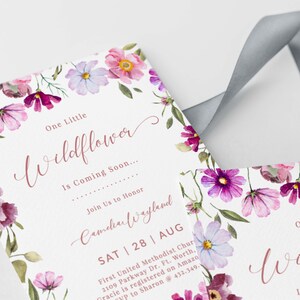 Pu&ograve; includere: Un invito a una festa di benvenuto per un bambino con un bordo floreale. L'invito recita "One Little Wildflower is Coming Soon... Join Us to Honor Camellia Wayland SAT | 28 | AUG First United Methodist Church 2109 Parkway Dr. Ft. Worth, Gracie is registered on Amazon RSVP to Sharon @ 432.349."