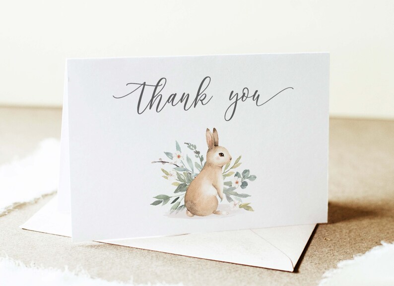 May include: A white thank you card with a watercolor illustration of a brown rabbit surrounded by green leaves and white flowers. The text "Thank you" is written in cursive on the card.